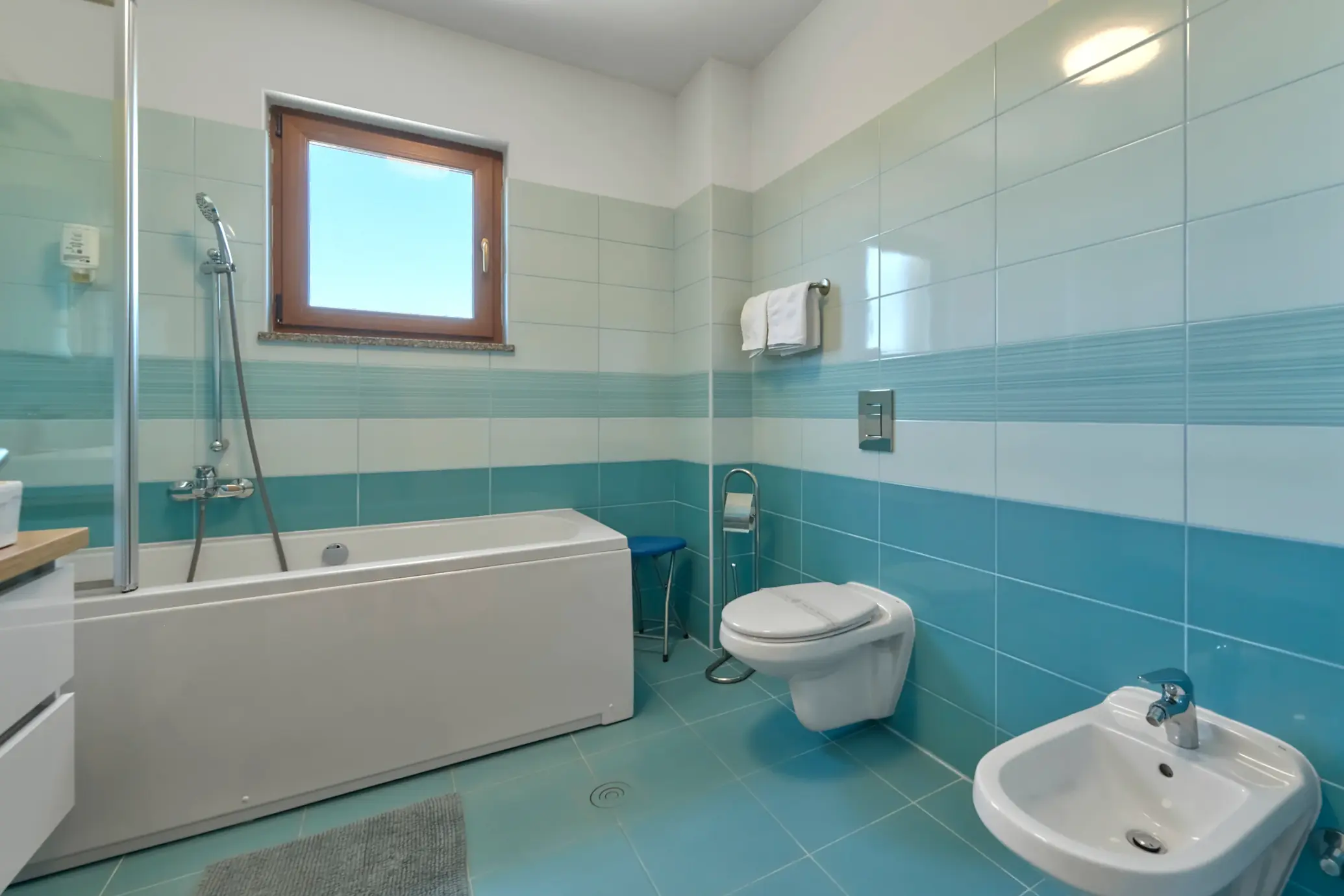 Badewanne, Waschbecken und WC im hellblau gefliesten Bad – Villa Štokovci, Ferienhaus in Istrien
