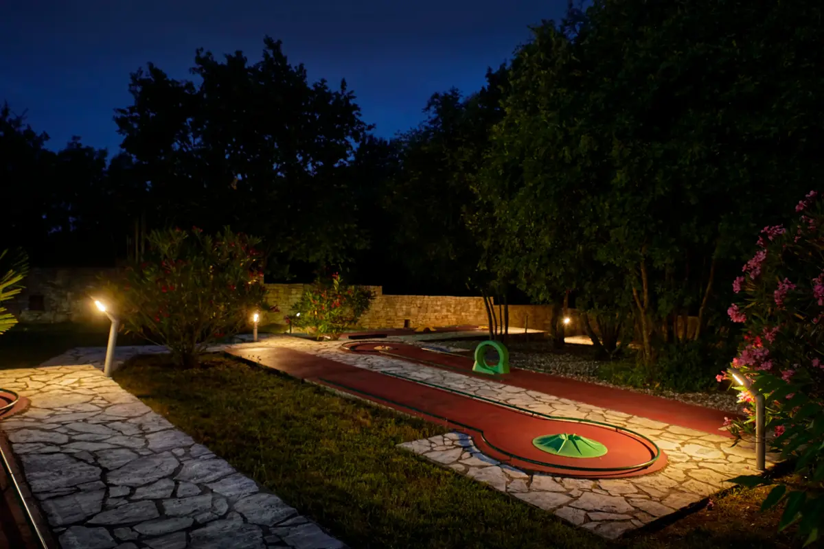 Beleuchteter Minigolfbereich unter Bäumen am Abend – Villa Štokovci, Ferienhaus in Istrien